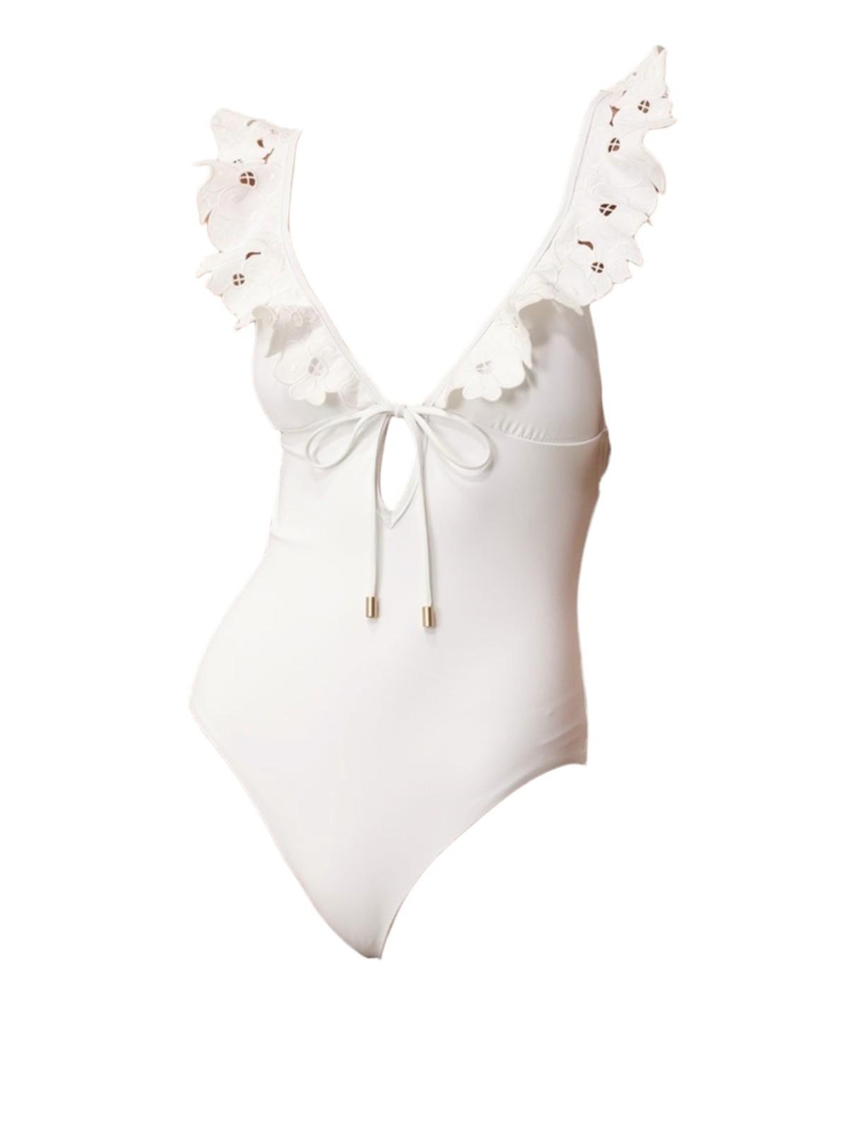 White swimsuit with floral lace details on a white background