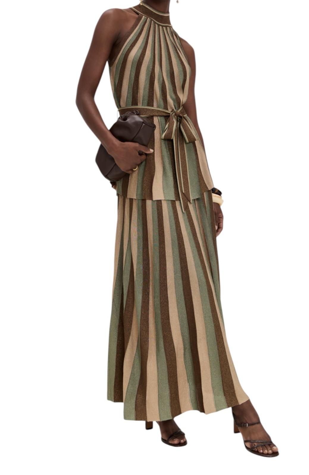 Woman wearing a striped dress holding a clutch on a white background