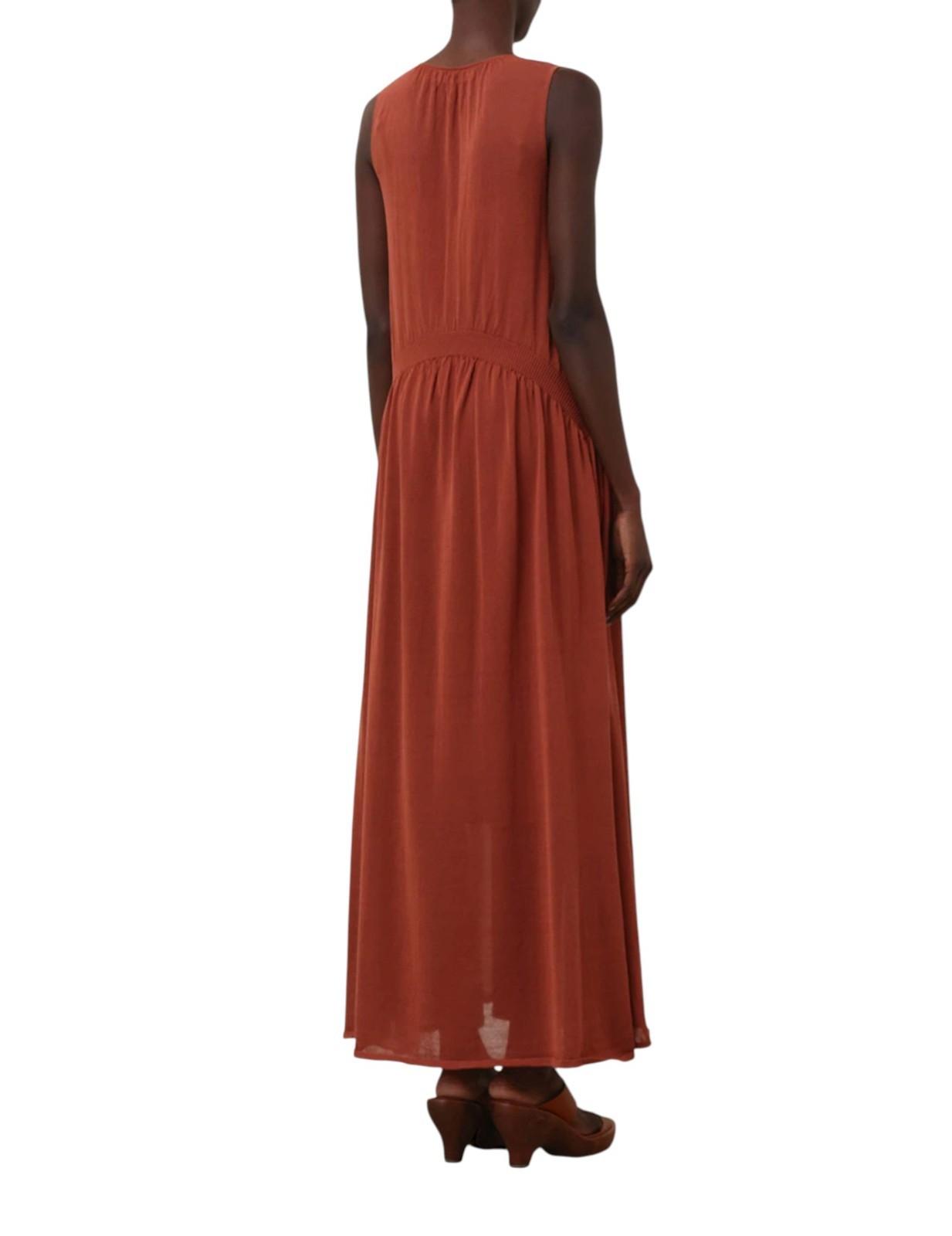 Person wearing a long rust-colored dress on a white background