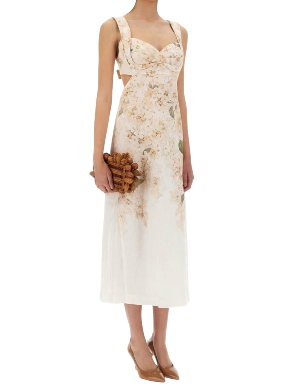 Woman wearing a floral dress holding a clutch on a white background