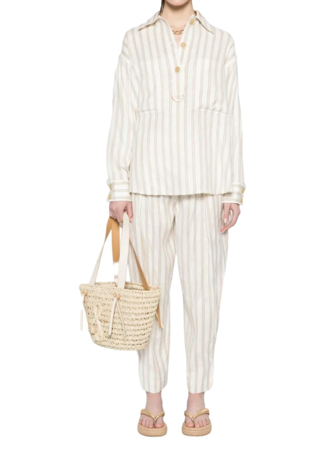 Person wearing a striped outfit holding a woven bag on a white background