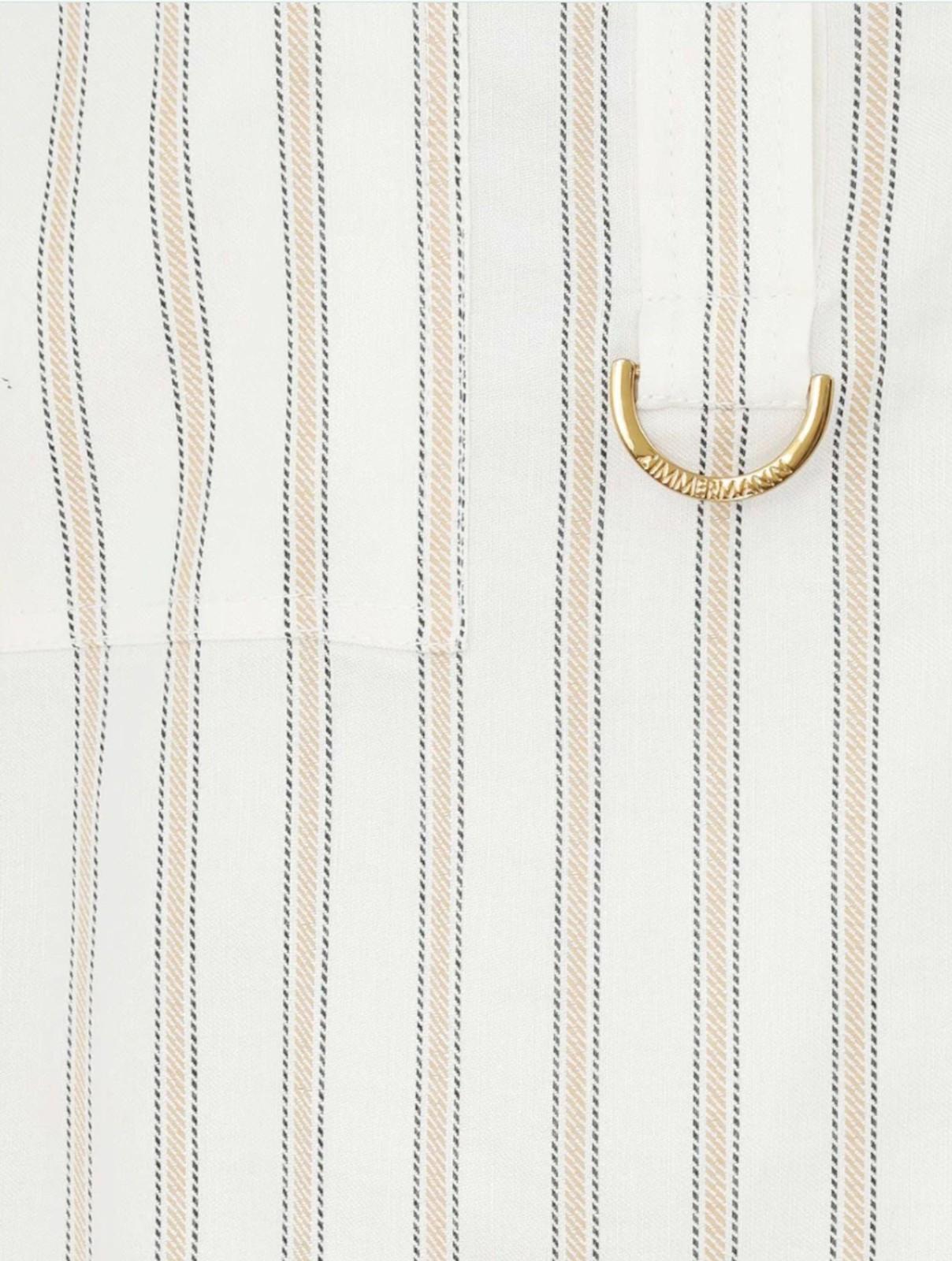 Close-up of a shirt with vertical stripes and a gold button on a white background