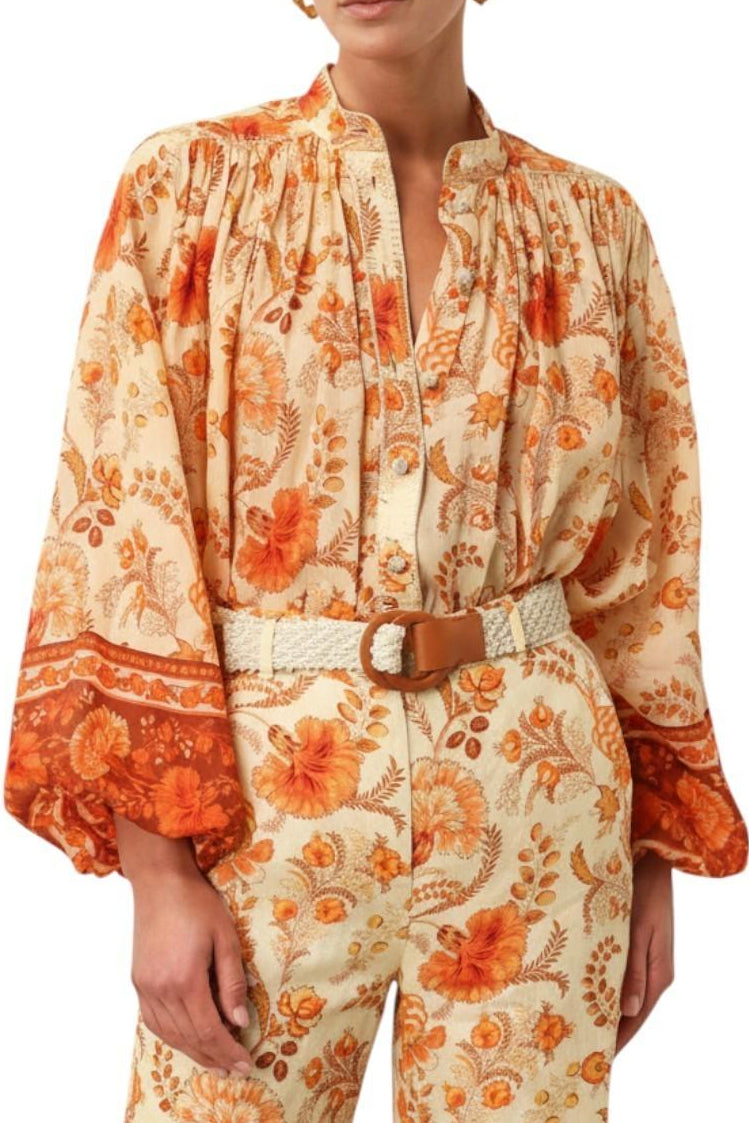 Woman wearing a floral patterned outfit with orange and beige colors on a white background