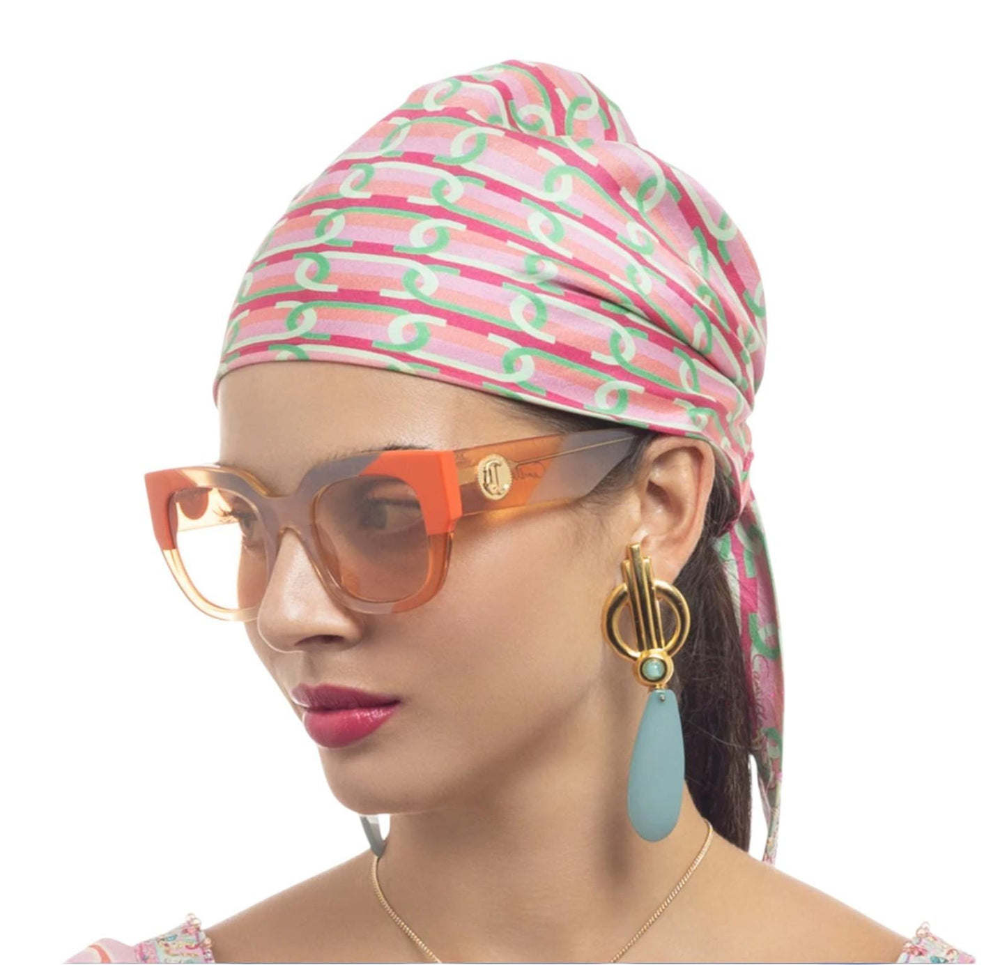 Woman wearing a colorful headscarf, sunglasses, and earrings on a white background