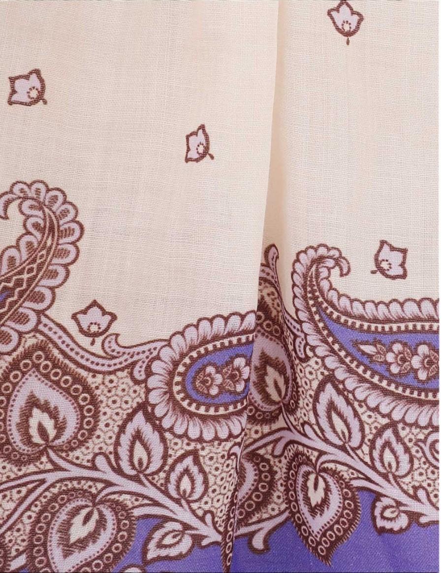 Close-up of fabric with intricate paisley pattern in brown and purple on a beige background