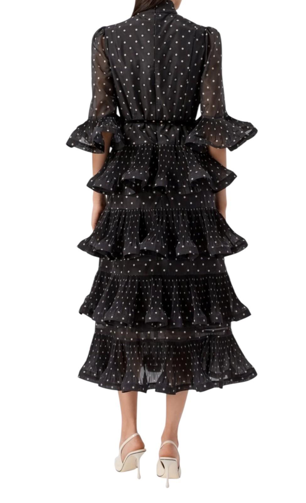 Black tiered dress with white polka dots on a white background