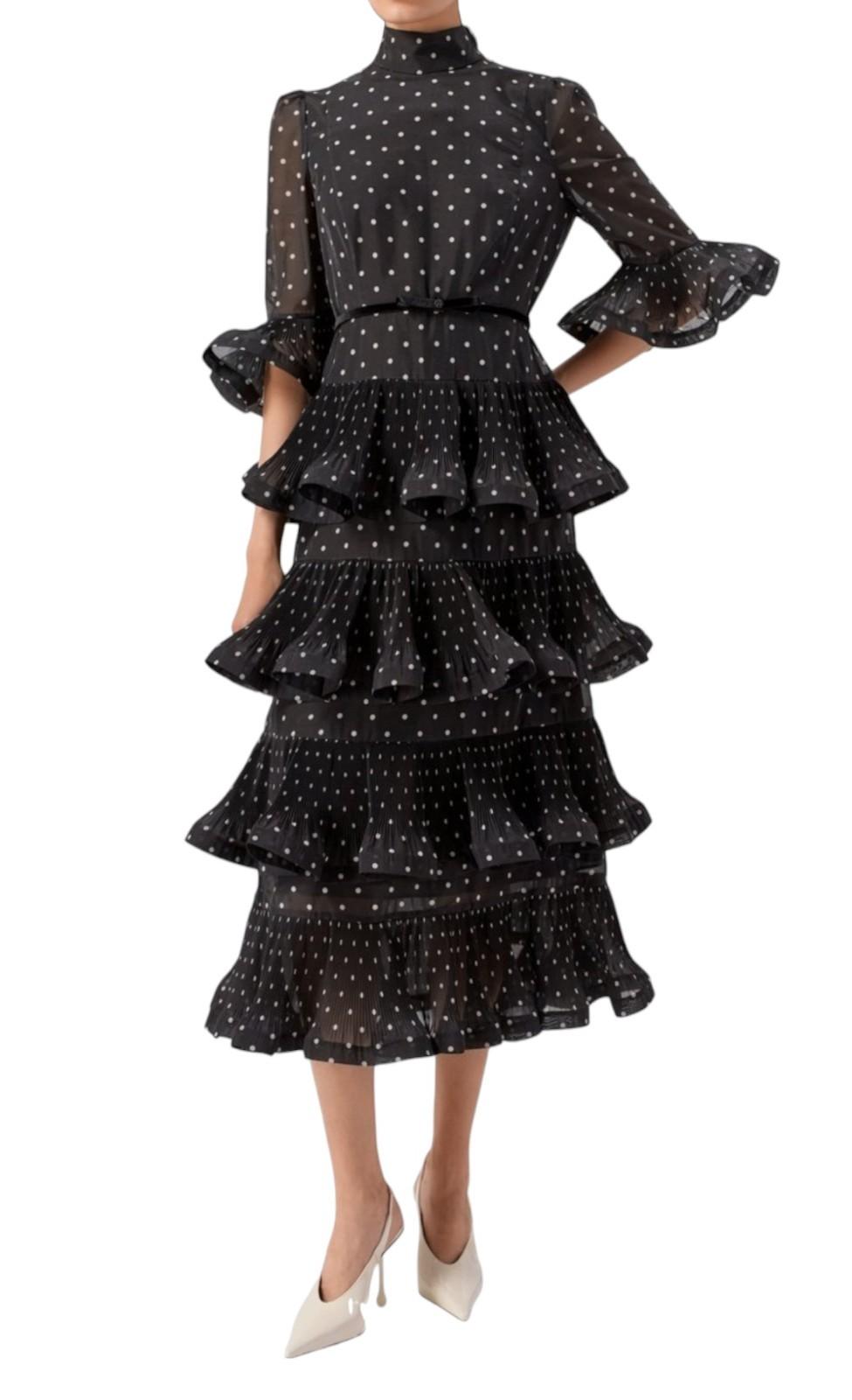 Black polka dot dress with ruffled layers on a white background