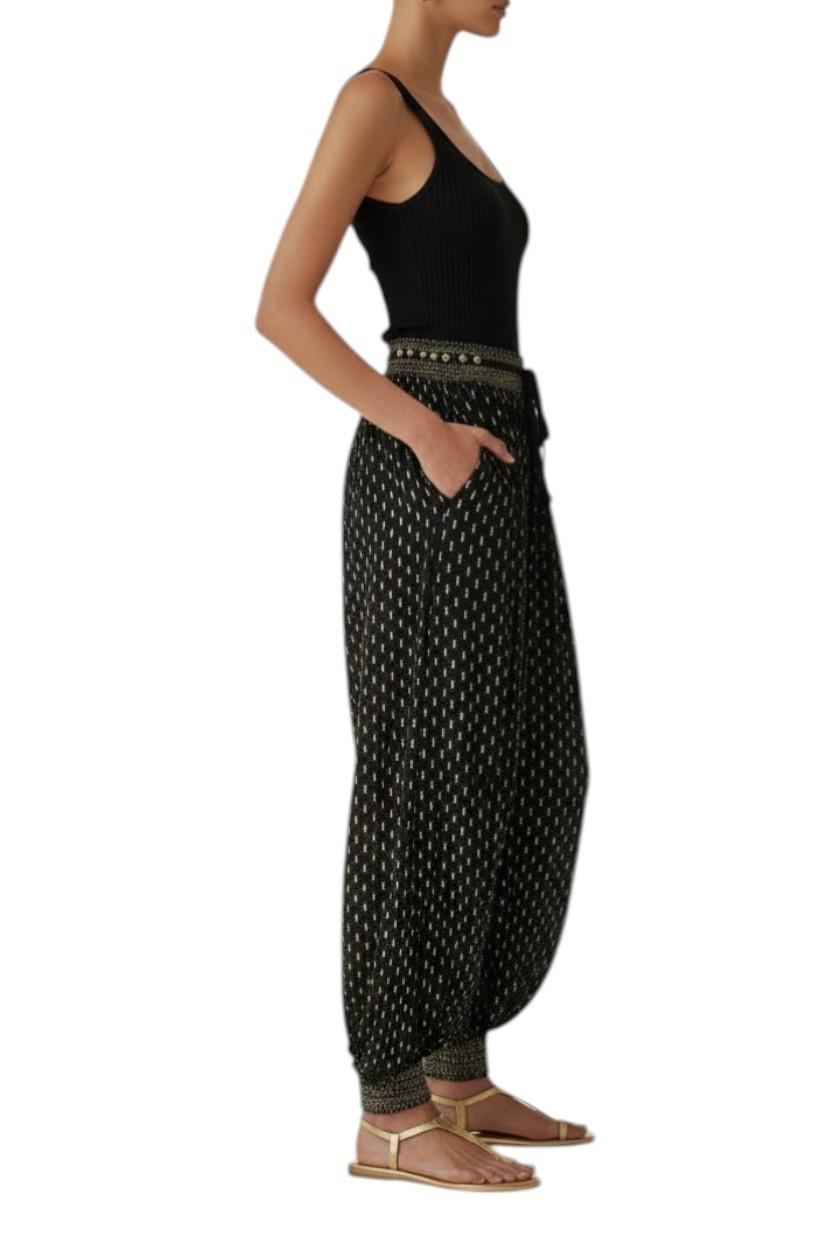 Woman wearing black patterned pants and a black top on a white background