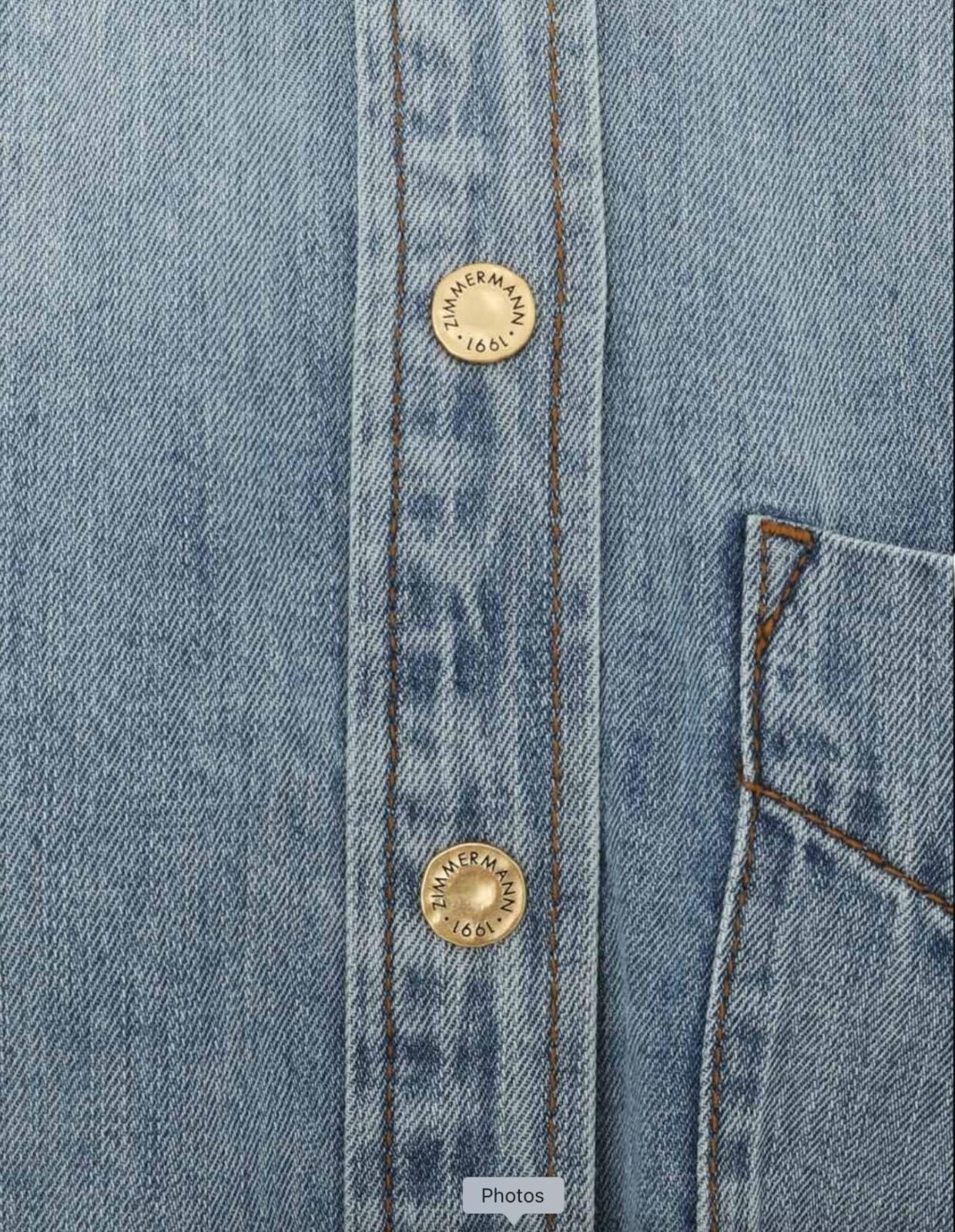 Close-up of a blue denim shirt with buttons and a pocket.