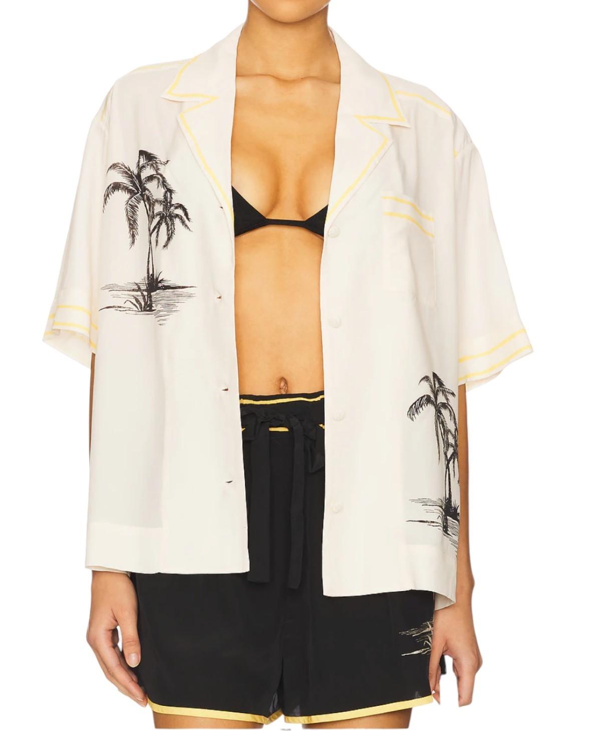 Person wearing a white kimono-style garment with palm tree designs over a black outfit.