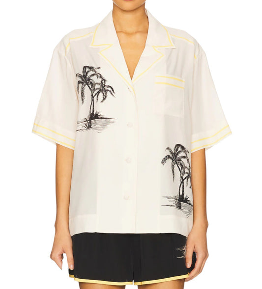 White shirt with palm tree design worn by a person on a white background