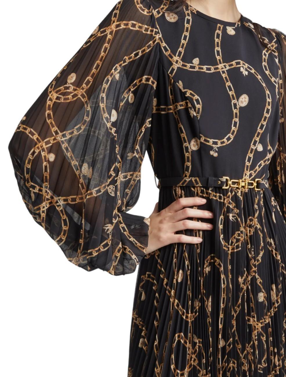 Black dress with gold chain pattern worn by a person on a white background