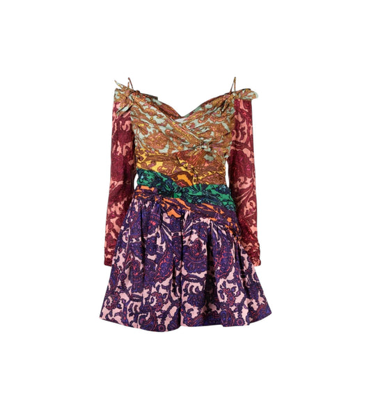 A short off-the-shoulder dress with a split patterned design: a metallic gold and orange patterned bodice with a green waistband, and a purple and pink paisley skirt, shown on a plain white background.