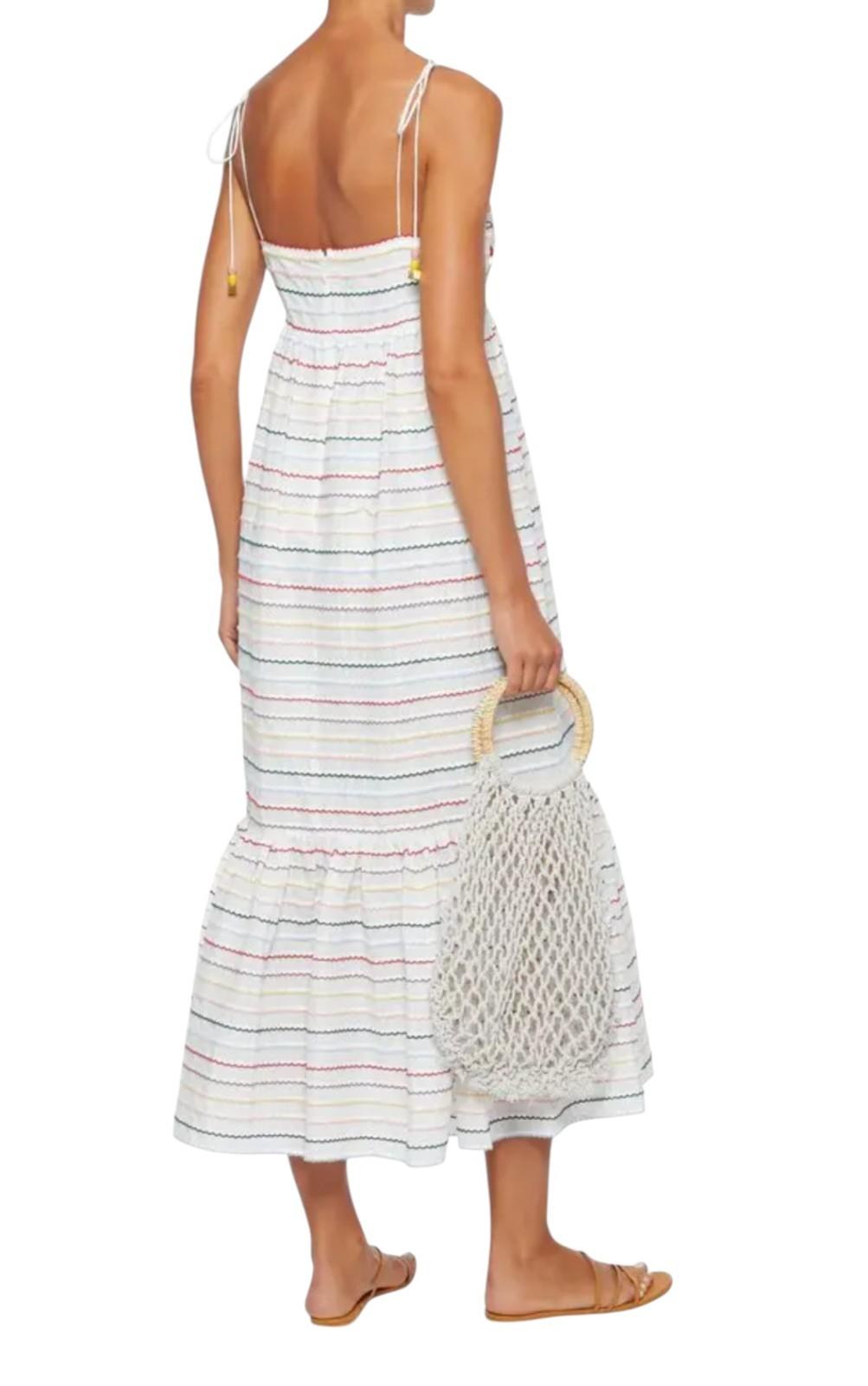 Woman wearing a striped dress holding a mesh bag on a white background