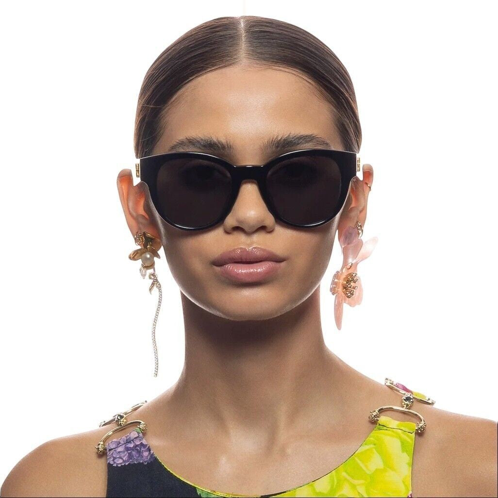 Naked Pear Camilla Sunday In the City round black sunglasses with gold hardware on a model wearing floral attire.