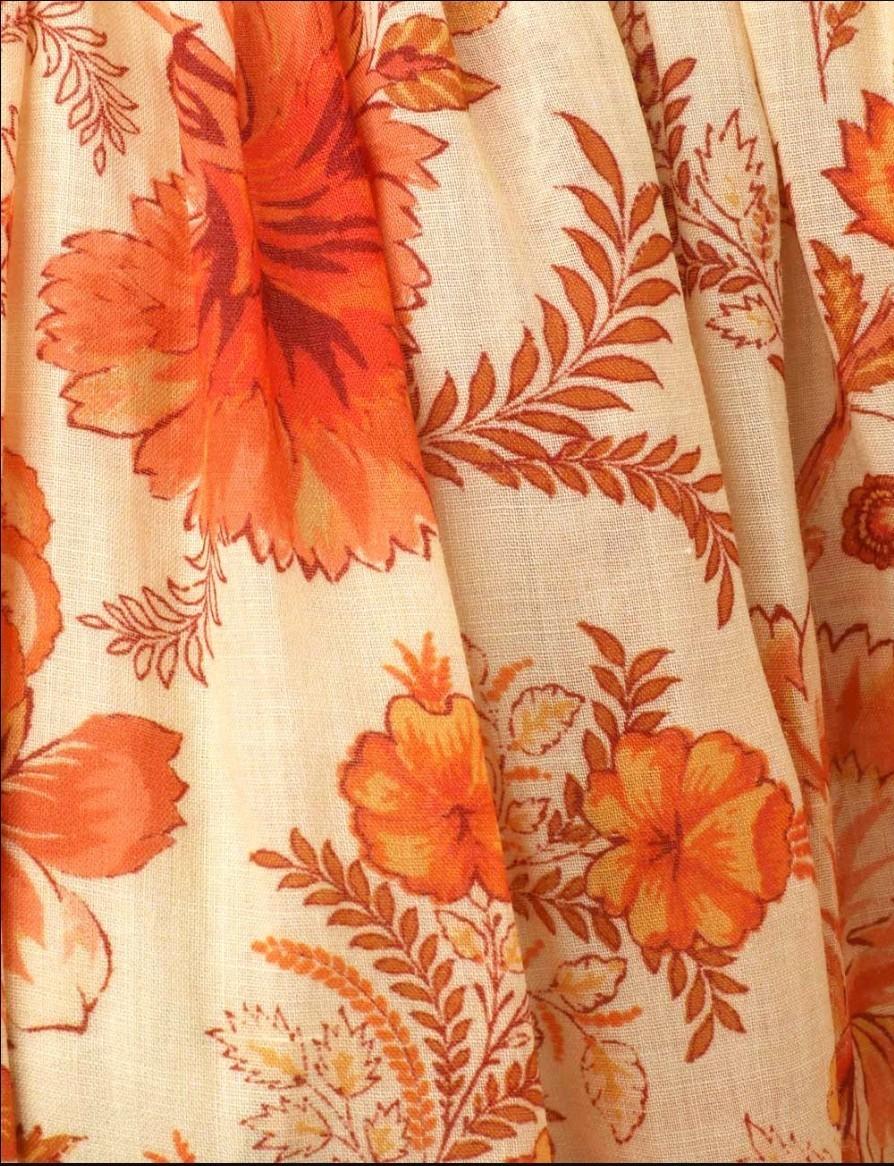 Close-up of fabric with orange floral pattern on beige background