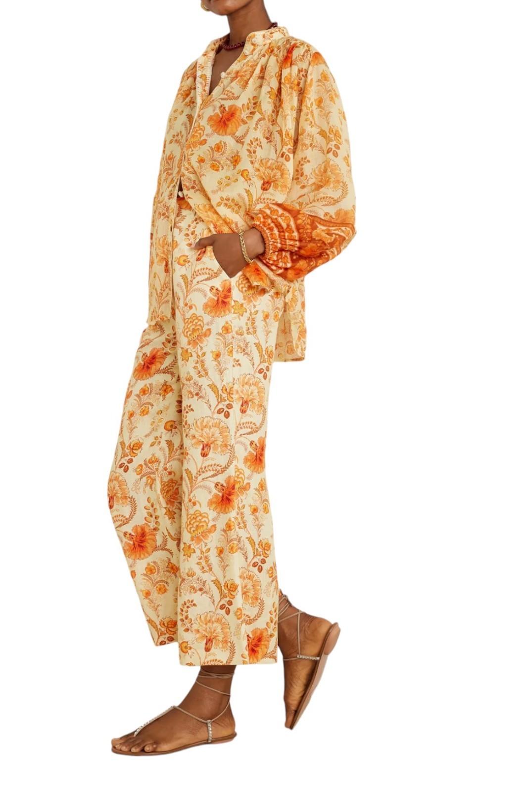 Woman wearing a floral pajama set with orange and beige pattern on a white background