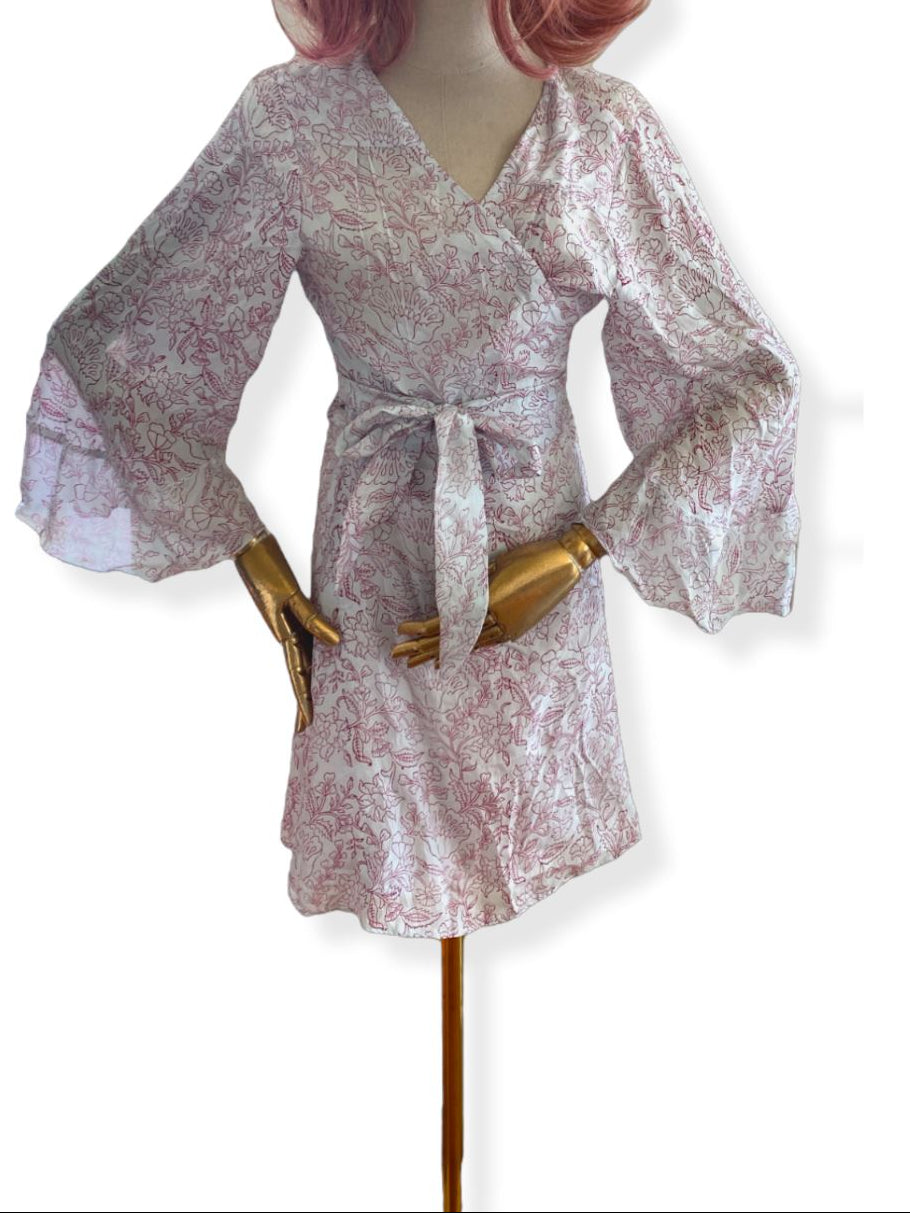 A mannequin displaying a white and red floral print wrap mini dress with flare sleeves and a tie-close neckline.